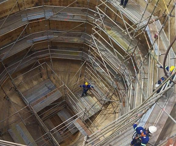 Vista aérea de estrutura de andaime multidirecional montada em operação industrial, com equipe trabalhando nos níveis.